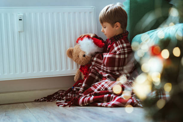 istock cute little boy wrapped id plaid sitting by heater 1652062427