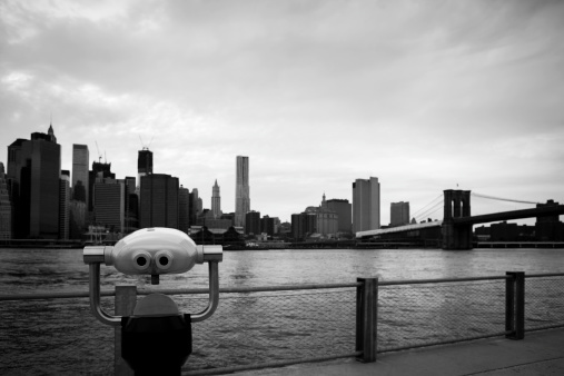 The lower Manhattan Skyline  and Brooklyn Bridge as seen from Brooklyn. Focus is on the observation binoculars in the foreground.