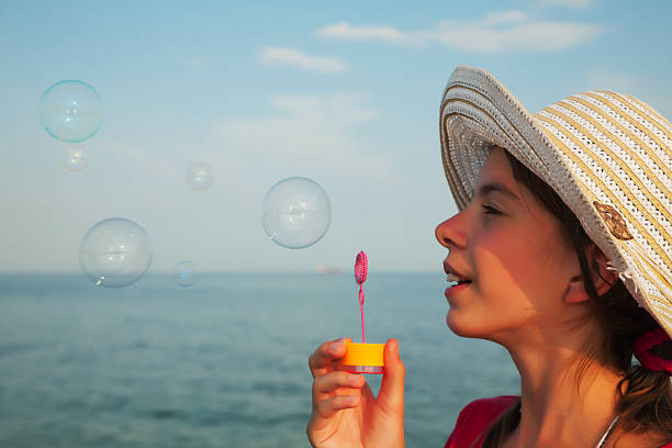 Teen girl blowing bubbles at sea shore