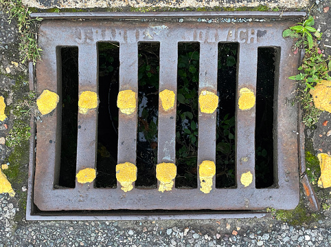 Old drain cover with yellow road markings