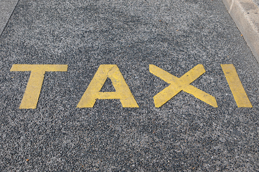 taxi sign painted on taxis car parking spot floor street road signage text