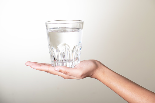 Glass of water in hand on grey background