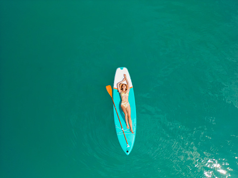 Aerial view of woman SUP boarding on lake in Alps in summer