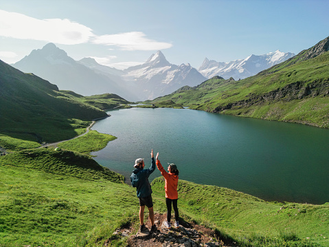 Aerial view  of man and woman  interchanging high-five  after the hike to the Bachalpsee lake in Swiss Alps