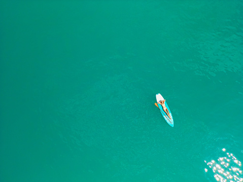 Aerial view of woman SUP boarding on lake in Alps in summer