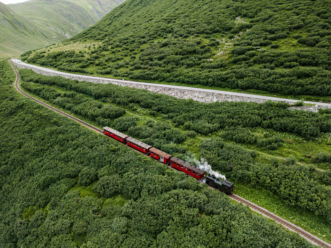 Aerial view of steam train passing Alpine meadow in Swiss Alps in summer