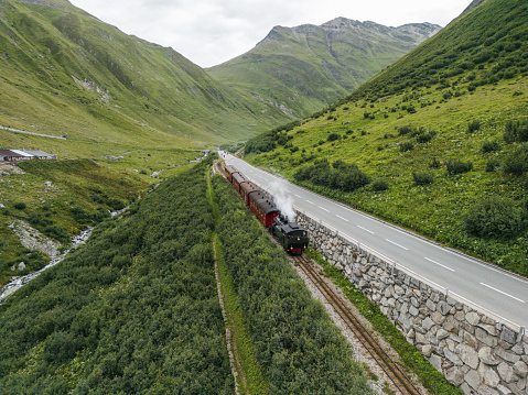 Aerial view of steam train passing Alpine meadow in Swiss Alps in summer