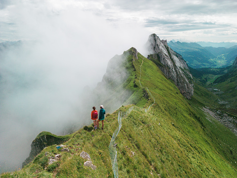 Aerial view of man and woman standing on top of mountain ridge  after rewarding climb in Switzerland in summer
