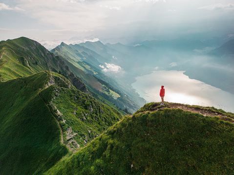 Aerial view of woman in red coat standing on top of the mountain ridge Augstmatthorn