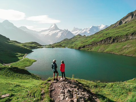 Aerial view  of man and woman  during the hike to the lake in Swiss Alps in summer