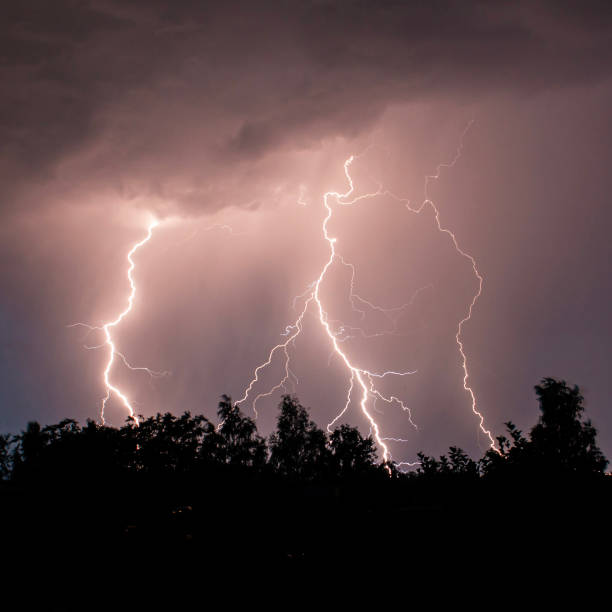 beautiful lightning during a thunderstorm at night in a forest that caused a fire, against a dark sky with rain