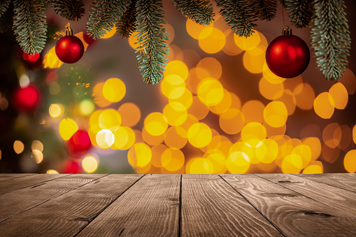 Empty rustic wooden table with defocused Christmas lights and baubles background. Predominant colors are yellow and red. High resolution 42Mp studio digital capture taken with SONY A7rII and Canon EF 70-200mm f/2.8L IS II USM Telephoto Zoom Lens