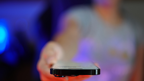 Woman holding a black mobile phone towards the camera close-up