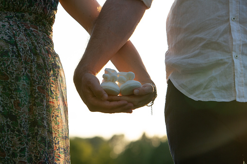 Conceptual image of gender reveal against homophobia: Couple waiting for the birth of their daughter with baby white shoes in hand