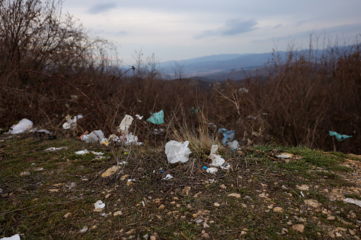 Hill with plastic rubbish against rural landscape on background
