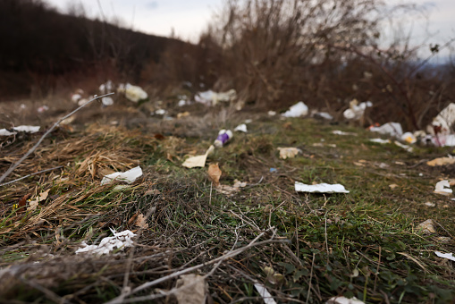 Hill with plastic rubbish against rural landscape on background