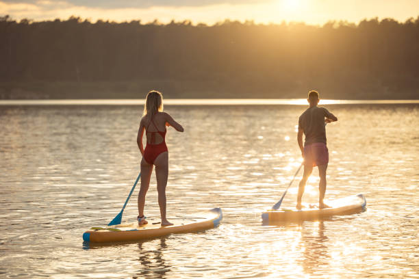 istock Man and woman sup board surfers at sunset. 1652308996
