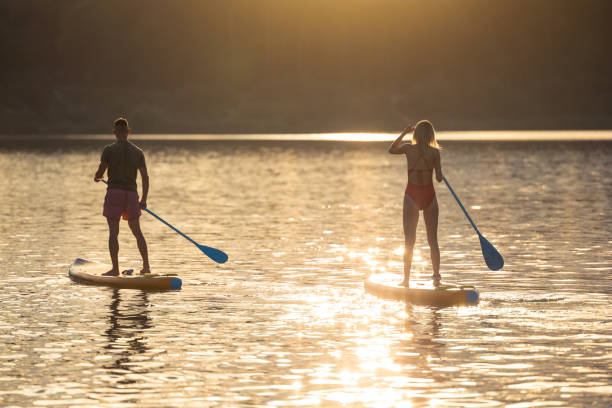 istock Man and woman sup board surfers at sunset. 1652308997