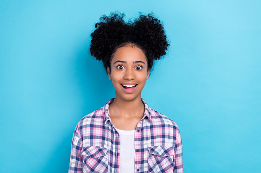 Photo of ecstatic impressed astonished girl with buns hairstyle wear plaid shirt staring at promo isolated on blue color background.