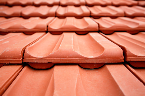 Close up, low angle view of new, red roof tiles. Abstract construction background.