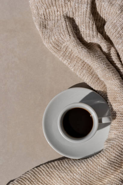 istock Hot coffee drink cup on neutral beige table background with light brown knitted cloth in sun light. Minimalist aesthetic morning coffee, cozy autumn concept. Flat lay, copy space 1652326936