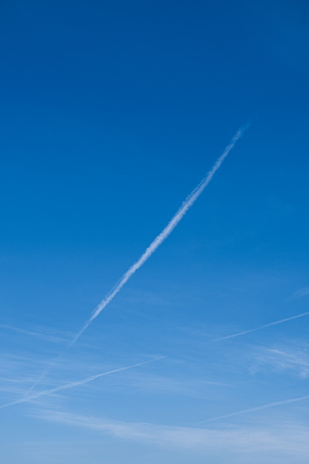 Airliner with contrails flying in a clear blue sky with beautiful cumulus clouds or cumulonimbus. Photography, Full frame.