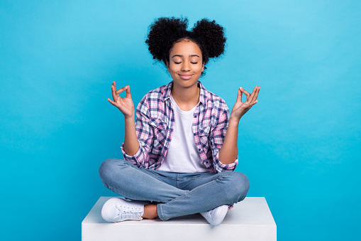 Photo of cheerful dreamy girl dressed checkered shirt closed eyes practicing yoga isolated blue color background.