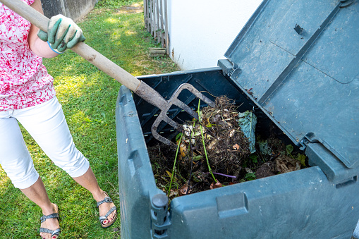 A woman and outdoor compost bin to reduce waste