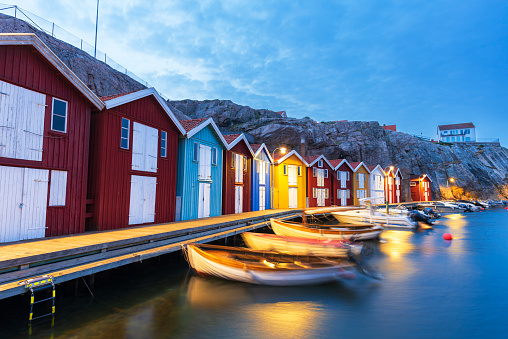 Illuminated iconic view of the typical colorful boathouses in the Smogen marina (Smögenbryggan) with boats, dusk time, Smogen, Bohuslan, Vastra Gotalan, Sweden, Scandinavia