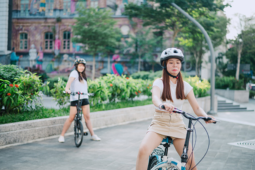 Asian Chinese young girl learning how to ride bicycle in city.