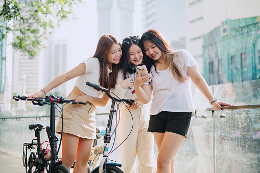 Three Asian young ladies looking at phone while having a rest during travelling