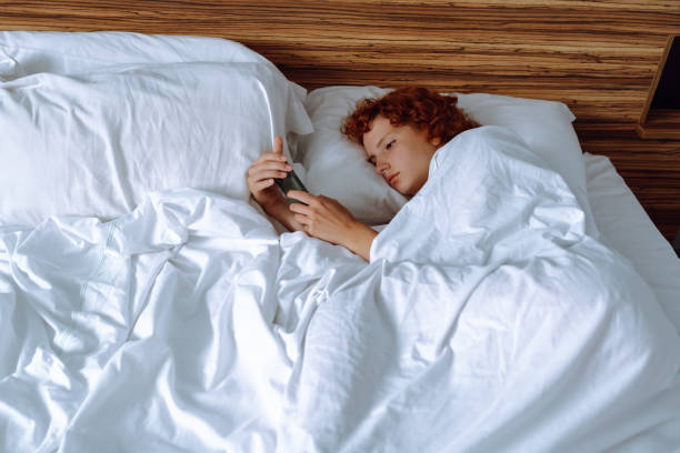 istock young red-haired girl in bed using gadget 1652386368