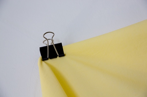 A metal clamp holding a piece of yellow fabric.