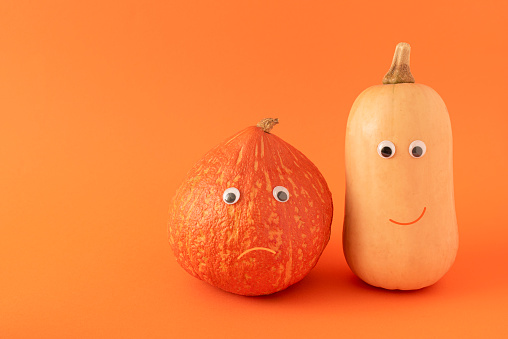 Creative idea made of two pumpkins decorated with eyes and glowing smiles. Minimal holiday concept.