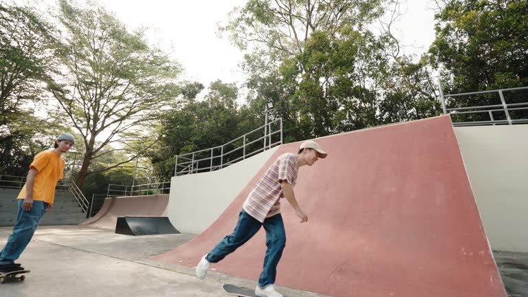 3 multiracial male friends skateboarding in skateboard park during weekend morning