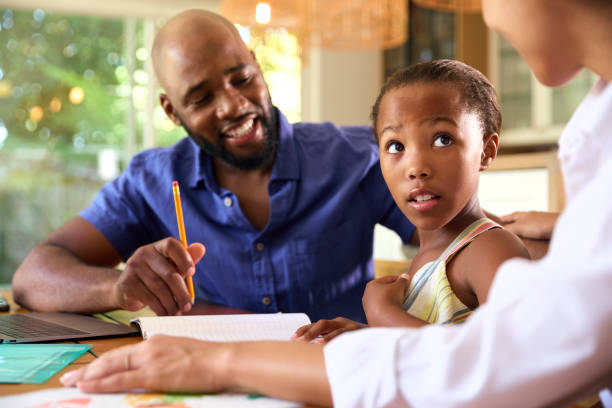 istock Family Around Table At Home Using Laptop With Parents Helping Daughter With Homework 1652435510