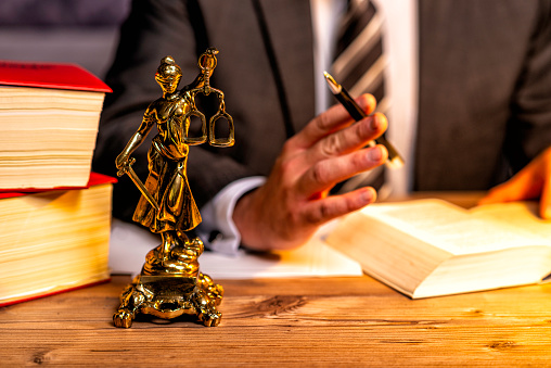 office of a lawyer with books and a statue of Lady Justice, goddess Justitia, on the desk
