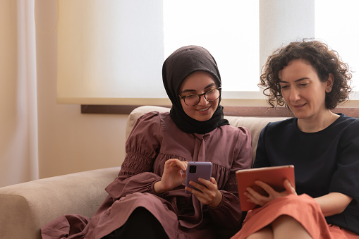 Two women's are accessing having a video call with a professional on digital tablet at home.