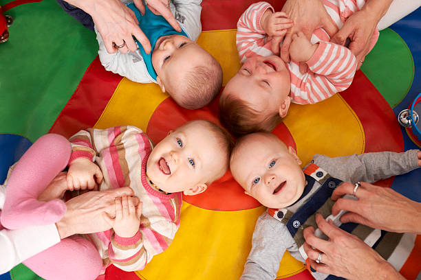 Overhead view of playing nursery babies Being tickled by mothers group of babies stock pictures, royalty-free photos & images