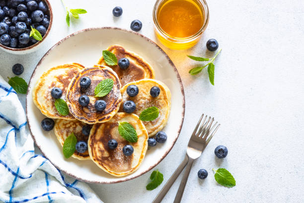 istock Pancakes with fresh blueberries and honey at white table. 1652465415