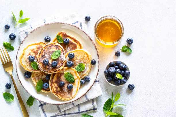 istock Pancakes with fresh blueberries and honey at white table. 1652465578