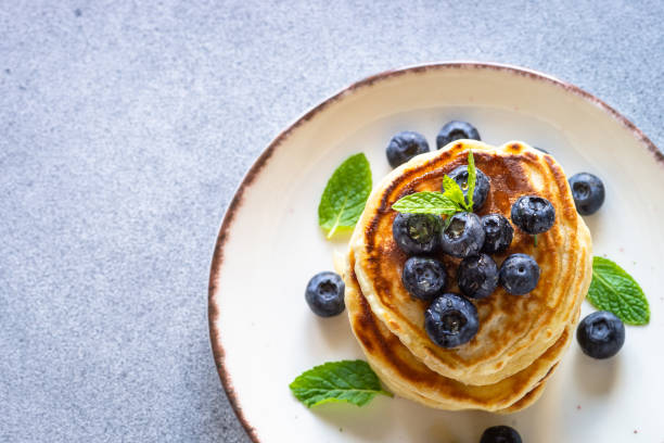 istock Pancakes with fresh blueberries and honey at white table. 1652465992