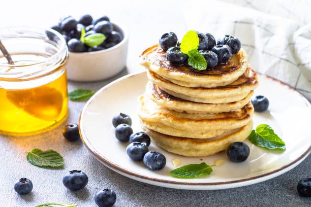 istock Pancakes with fresh blueberries and honey at white table. 1652466541
