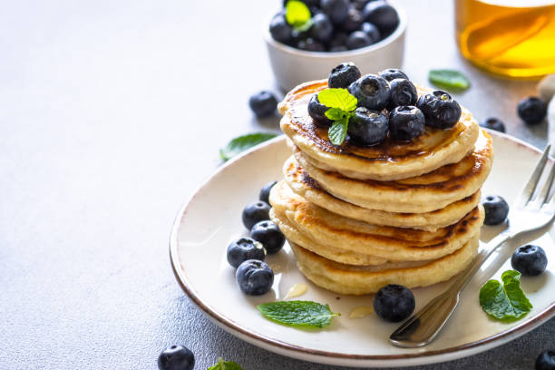 istock Pancakes with fresh blueberries and honey at white table. 1652467099