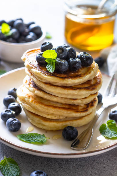 istock Pancakes with fresh blueberries and honey at white table. 1652469916