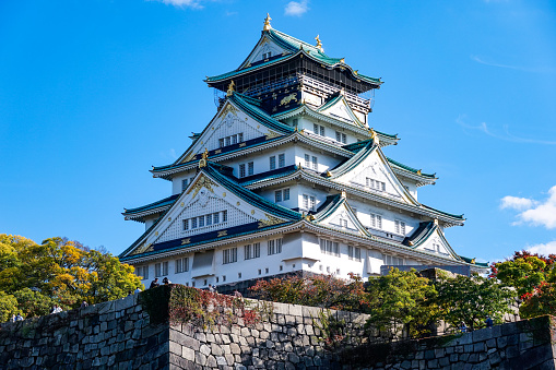 The Osaka Castle tower with a clear autumn sky and colored leaves in Shiromi, Osaka City, Osaka Prefecture, on a sunny day in November 2022