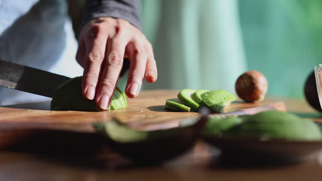 An Asian Woman cutting and opening an avocado close up