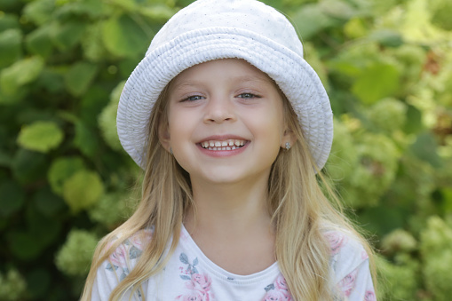 Portrait of preschool girl with straw hat. Cute happy toddler child looking at the camera and smiling. Lovely girl on summer vacations with family