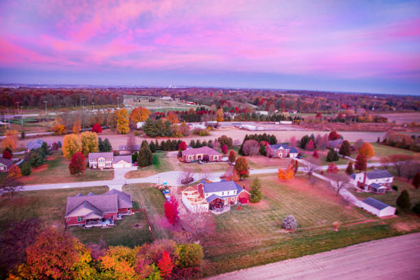 A drone view looking at a suburb. One of the houses is having major construction renovations. The scene is in early Autumn.