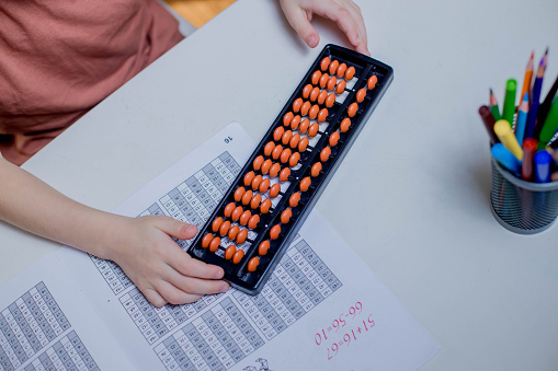Abacus and colored pencils on a white table. Learning mental arithmetic